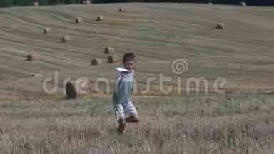 快乐的少年男孩在收获的田野背景下玩纸飞机